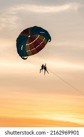 Couple Paragliding In A Coloured Parachute