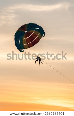 Couple paragliding in a coloured parachute
