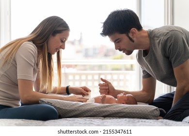 a couple of parents changing the diapers to their newborn son on the bed - Powered by Shutterstock