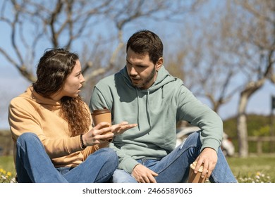 couple in park arguing because they disagree. Young couple on a sunny day arguing about housework or work. Couple talking seriously outdoors in a park. - Powered by Shutterstock