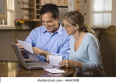 Couple Paying Bills Online With Laptop Computer At Home.