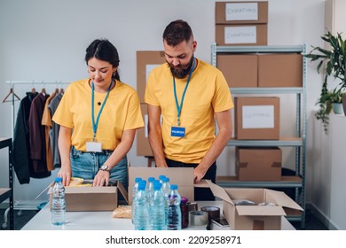 Couple Of People Working On Humanitarian Aid Project. Teamwork In Homeless Shelter. Two Volunteers Working In A Community Charity Donation Center. Copy Space.