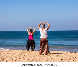 A couple is performing qigong exercises at the beach of Goa - Powered by Shutterstock