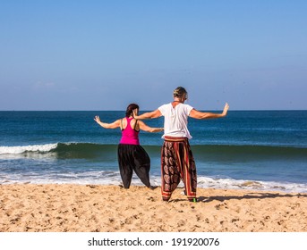 A couple is performing qigong exercises at the beach of Goa - Powered by Shutterstock