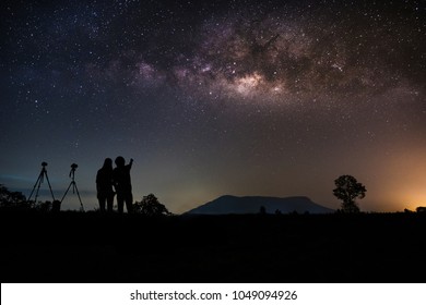 Couple Photographer Standing Near The Camera And Looking Milky Way And Stars On The Sky At Night.silhouette Style.