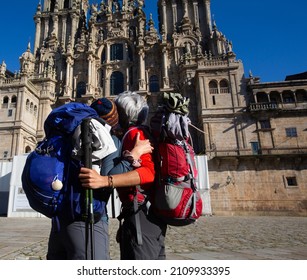 A couple of pilgrims celebrate in front of the cathedral of Santiago that they have reached the end of the journey after walking the Camino de Santiago