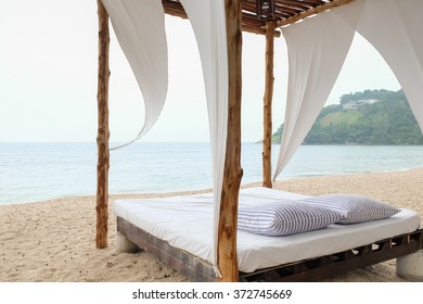 A Couple Of Pillows On Beach Bed And White Sand 
