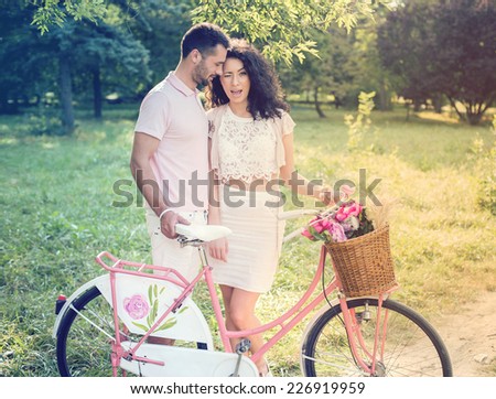 Couple with pink vintage bicycle in the summer park on a sunset