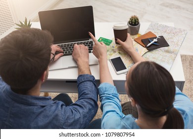 Couple Planning Travel. Unrecognizable Man And Woman Searching Or Booking Tickets Online With Blank Laptop And Credit Card, Preparing For Summer Vacation, Back View, Copy Space