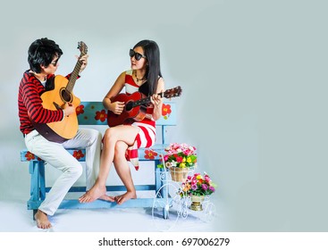 Couple Play Guitar On The Chair.happy Family And Music Time. Asia Man And Woman Play Guitar In Holiday. Portrait On Blue Background.