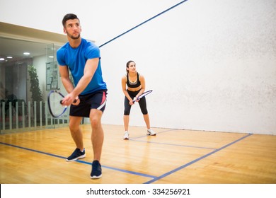 Couple play some squash together in the squash court - Shutterstock ID 334256921