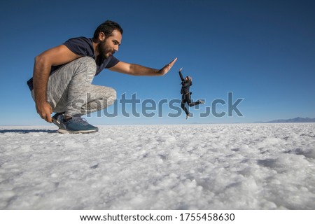 Couple playing in the desert salt flats, having fun with perspective