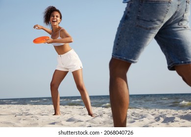 Couple playing with flying disk at beach on sunny day - Powered by Shutterstock