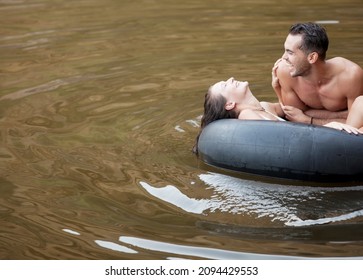 Couple Playing In Inner Tube On Lake