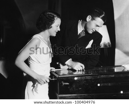 Couple playing with pinball machine