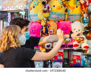 A Couple Playing Shooting Range At An Amusement Park During A Date