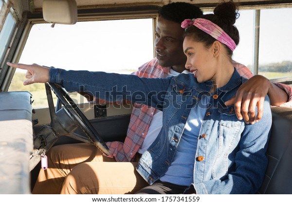 Couple pointing at distance while driving a\
car at countryside