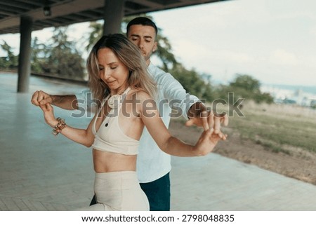 A couple practices a slow partner dance under a pavilion, sharing a relaxed, intimate summer moment.