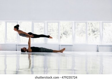 Couple Practicing Acro Yoga In White Studio. Acro Yoga Concept. Pair Yoga. Yoga Flexibility Class Workout