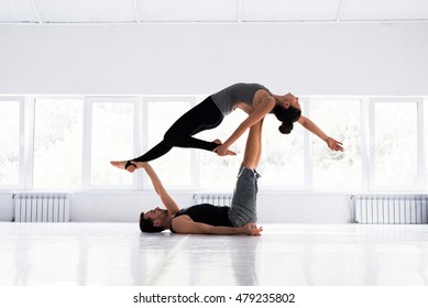 Couple practicing acro yoga in white studio. Acro yoga concept. Pair yoga. Yoga flexibility class workout - Powered by Shutterstock