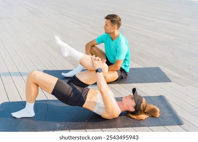 Couple Practicing Fitness Exercises on Yoga Mats Outdoors Near a Wooden Deck in Bright Sunlight - Powered by Shutterstock