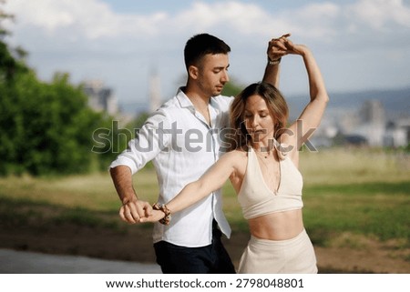 Couple practicing a graceful partner dance outdoors, showing movement, connection and relaxed summer style.