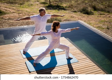 Couple practicing yoga on at poolside on a sunny day - Powered by Shutterstock