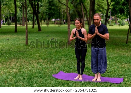 couple practicing yoga outdoors in a city park doing meditation exercises with namaste gestures people focus mental and spiritual health