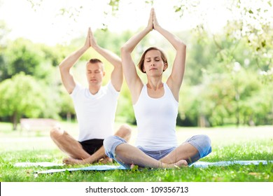 Couple Practicing Yoga In The Park
