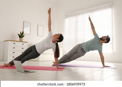 Couple practicing yoga while watching online class at home during coronavirus pandemic. Social distancing - Powered by Shutterstock