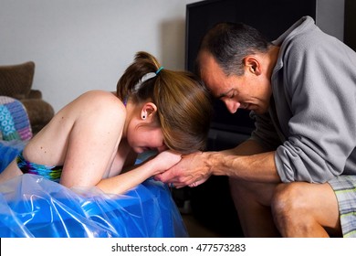 A couple prays together as the wife labors in a birthing pool.  The husband looks serene and the wife is obviously in pain with a contraction.
