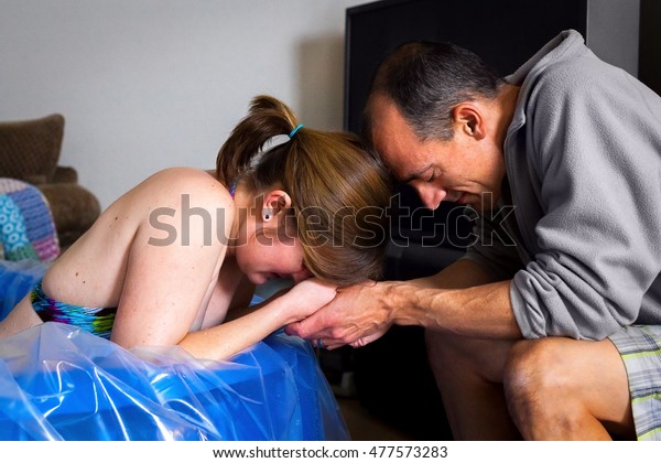A couple prays together as the wife labors\
in a birthing pool.  The husband looks serene and the wife is\
obviously in pain with a\
contraction.