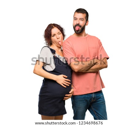 Couple with pregnant woman showing tongue at the camera having funny look on isolated white background