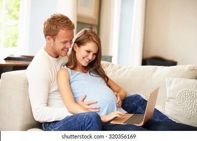 Couple With Pregnant Woman Using Laptop Computer Together