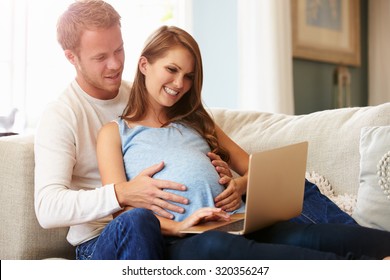 Couple With Pregnant Woman Using Laptop Computer Together