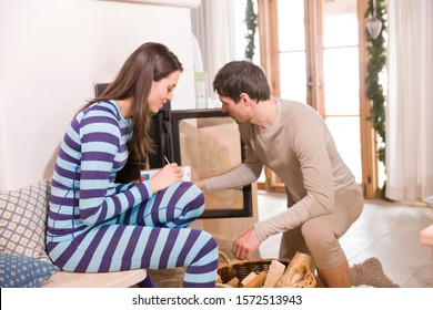 Couple Preparing Fire In Log Cabin