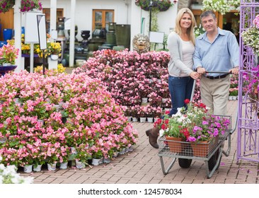 Couple Pushing A Trolley In Garden Centre While Smiling