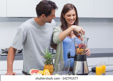 Couple putting various fruits into blender - Powered by Shutterstock