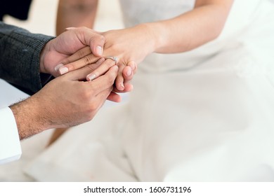 couple putting wedding rings  - Shutterstock ID 1606731196