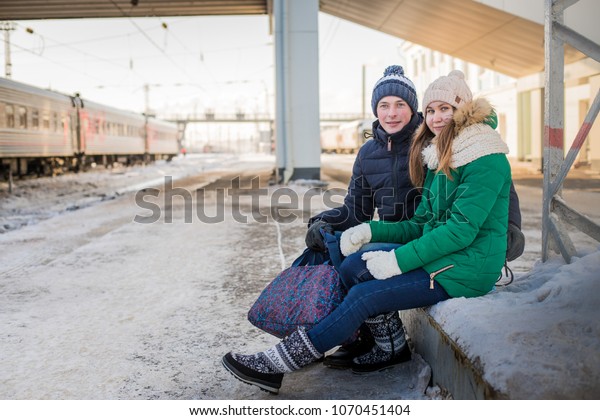 Couple at railway station near train in a winter\
time and snow around