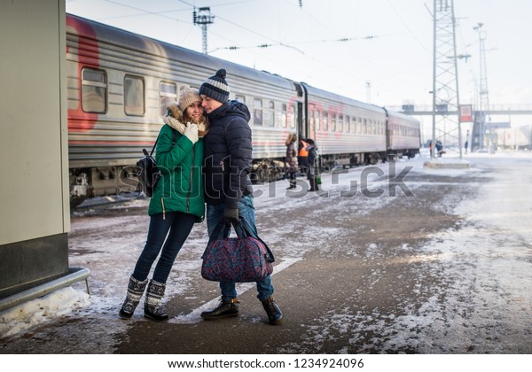 Couple at railway station near train in a winter\
time and snow around