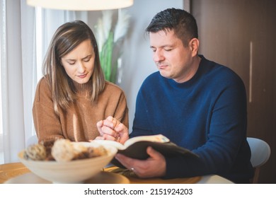Couple reading bible and pray together at home - Shutterstock ID 2151924203