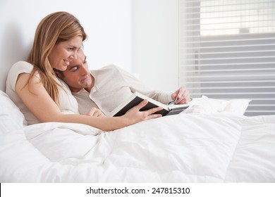 Couple Reading A Book Lying In The Bed