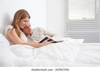 Couple Reading A Book Lying In The Bed