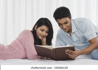 Couple Reading A Book On The Bed