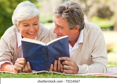 Couple reading a book in the park - Powered by Shutterstock