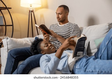 Couple reading books while resting on sofa together at home - Powered by Shutterstock