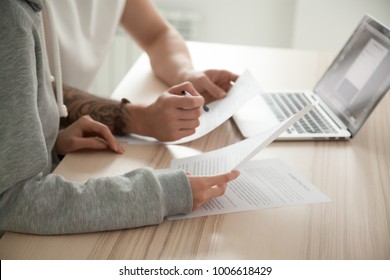 Couple reading legal documents at home with laptop, family considering mortgage loan or insurance, studying contract details, discussing terms and conditions, close up view of hands holding papers - Powered by Shutterstock