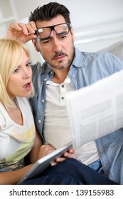 Couple Reading News With Horrified Look