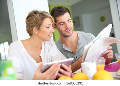 Couple Reading News On Digital Tablet